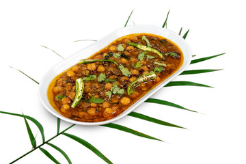 A white plate of Channa Masala, an Indian dish of chick peas and curry spices on a palm leaf isolated on white
