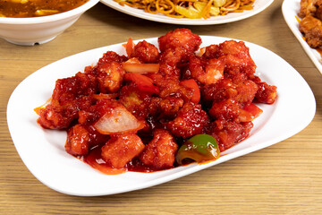 Chinese and Asian dish Sweet and Sour Chicken on a white plate on a wooden table