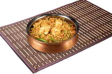 Indian cuisine paneer biryani, rice and cheese and vegetables served in a  traditional copper dish  isolated on white