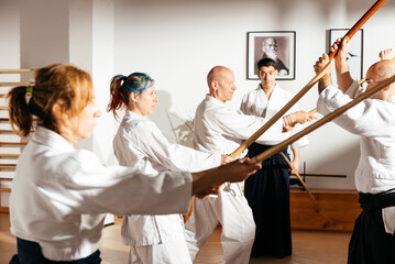 Female Student Practices Wooden Sword Techniques in a Martial Arts Dojo With Peers