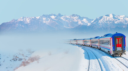 Red diesel train (East express) in motion at the snow covered railway platform - The train connecting Ankara to Kars - Passenger train going through tunnel 
