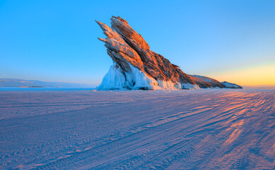 Beautiful winter landscape of frozen Lake Baikal at sunrise - A granite rock with steep slopes...