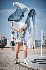 Young sexy girl in space silver micro skirt dancing with performance fan waving gracefully, female...