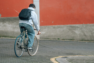 young man or student with backpack riding on vintage bicycle
