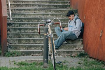 student sitting on the street with mobile phone and bicycle