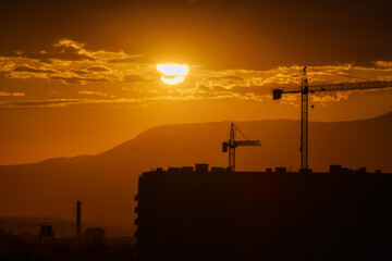 The stunning silhouette of a construction crane at sunset in the urban cityscape
