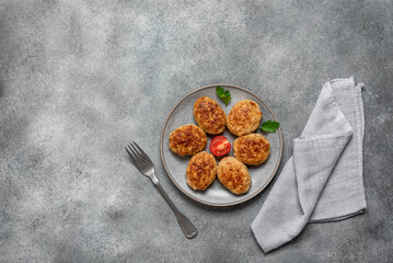 Fried meat cutlets in a plate on a gray concrete background. Top view, flat lay.