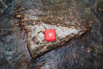 Red first aid kit for emergency medical care in the outdoors. Ideal for rocky surfaces in streams...