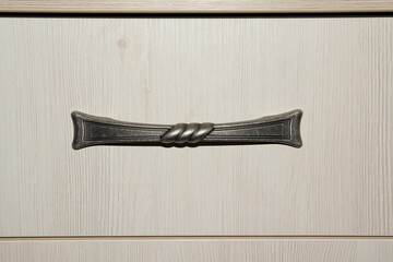 Bronze handle on the doors of an antique oak cabinet