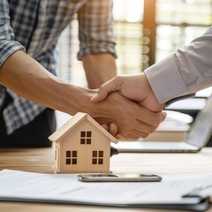 Two men shaking hands over a house model