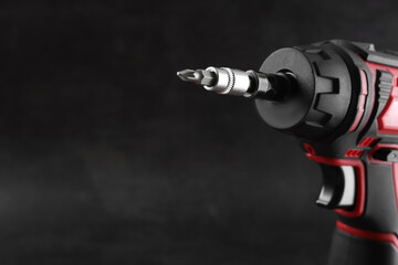 Modern electric screwdriver on dark grey background, closeup. Space for text