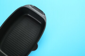 Black pot on light blue background, top view. Space for text