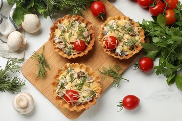 Tasty tartlets with cheese, tomatoes, mushrooms and dill on white table, flat lay