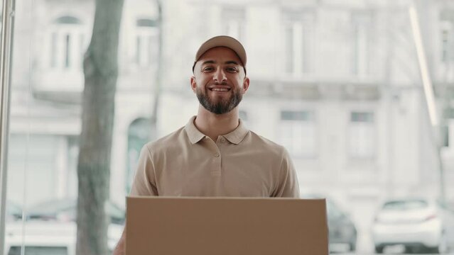 A cheerful bearded courier in a cap presents a parcel, exemplifying efficient delivery service and customer satisfaction.