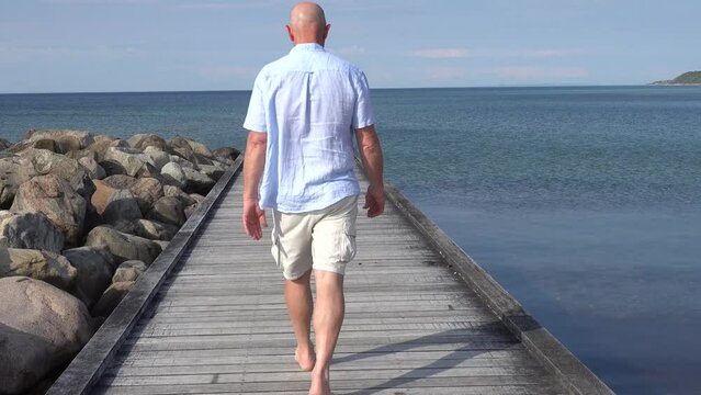 Tisvilde, Denmark A man walks on a boardwalk on the beach in North Zealand on the Kattegat.