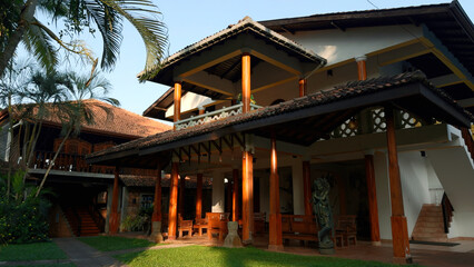 Luxury cottage with lush green bushes and long coconut trees. Action. Concept of summer vacation.