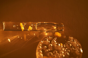 Pipette with serum shimmering in the sun on a beige background.