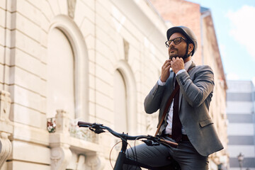 Businessman adjusting cycling helmet while going to work with  bicycle.