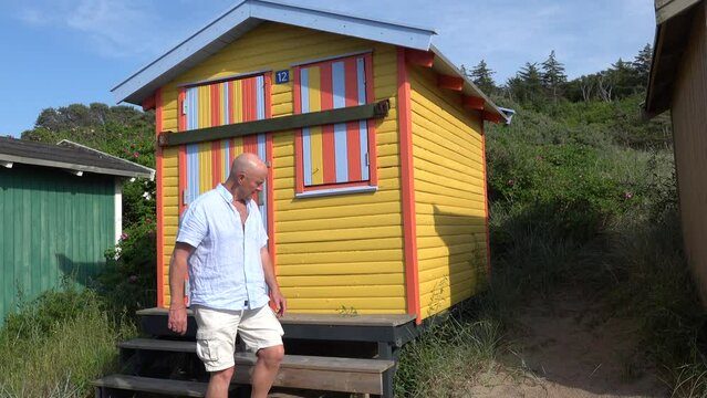 Tisvilde, Denmark A man walks past a colourful beach hut on the beach