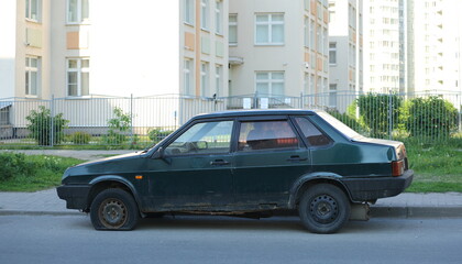 An old dark green car is parked in the courtyard of a residential building, Soyuz Prospekt, Saint...