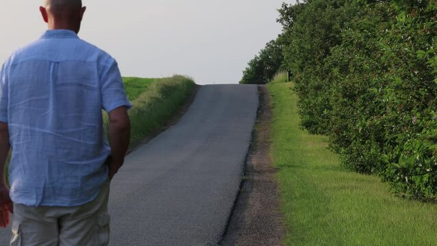 Tisvilde, Denmark A man walks alone on a country road in the summer
