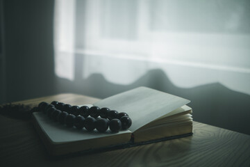 Bible and rosary placed on a wooden table after praying to God which is a Christian religious...