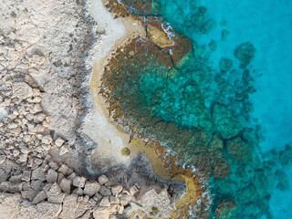 Aerial view on a rocky cove beach with abstract pattern. Clear turquoise Mediterranean sea in Ayia Napa, Cyprus.