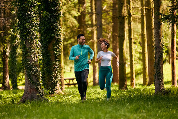 Full length of happy sports couple running together in nature.