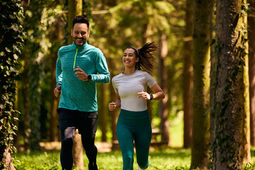 Happy couple of athletes jogging in nature.