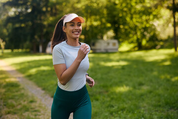 Young happy sportswoman jogging in  park.