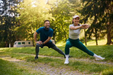 Happy couple doing stretching exercises while working out in nature.