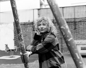 Analogue portrait of confident woman leaning on swing structure.