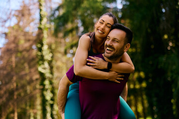 Happy athletic couple piggybacking while working out in park.