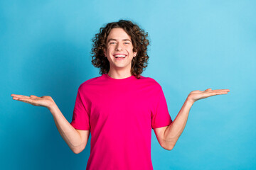 Portrait of good mood man with curly hair piercing wear pink shirt palms comparing products empty...