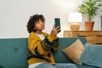 African American girl holding smartphone having video chat. Female blogger chatting with best...