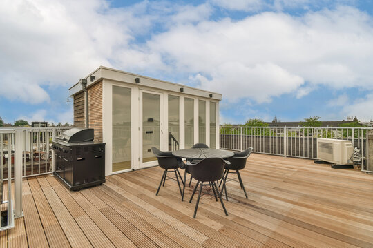 Modern rooftop patio with dining set and grill