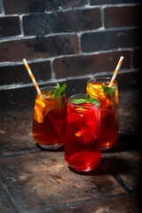glasses of refreshing iced tea, fruity and black on dark background
