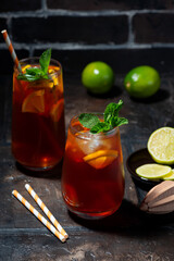iced tea with lime and fresh mint on dark background, vertical
