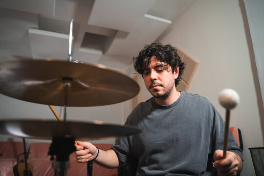 Young male drummer playing in a home studio setup