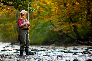 Fly fishing woman during Autumn fall foliage colorful leaves in a river in Vermont, New England