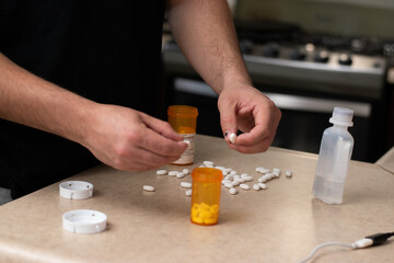 Man desesperated and addicted with many pills and syringes front him in a table