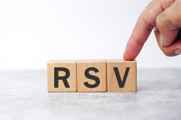 Woman hands point RSV – (Respiratory Syncytial Virus) acronym word on wooden cube, Front View, Copy space, medical concept background.