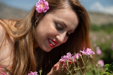 Young and beautiful woman smelling pink roses in a rose field. Famous Isparta rose.