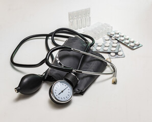 blood pressure monitor is on a white table with pills and ampoules