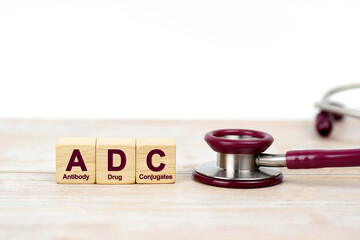 Word ADC on wooden blocks and stethoscope on the wooden table with white background for copy space....