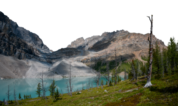 A set of large rocky mountains behind a light blue lake with a grassy hill and trees in the foreground. The sky is transparent.

