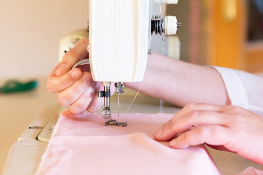 Close-up of hands sewing fabric on a sewing machine