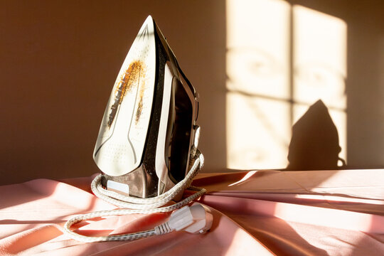 Sunlit iron on pink fabric in a sewing environment