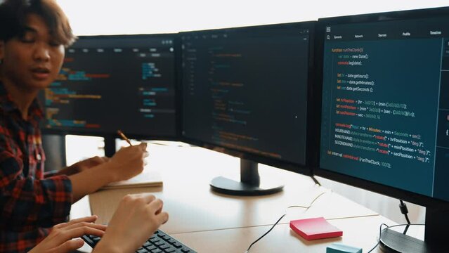Slow motion back end software developer engineer for computer programming working together on debugging writing computing code, solving complex algorithms display on monitor in office. Burgeoning
