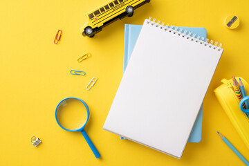 Flat lay of back to school stationery items including notebook, paper clips, magnifying glass, and...